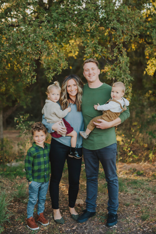 A family with three kids in front of the forest